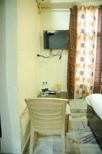een kamer met een stoel, een tafel en een raam bij Hotel Sachidanand in Shirdi