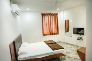 a white room with a bed and a television at Hotel Aaram Kalupur in Ahmedabad