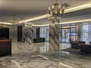 a lobby with marble floors and a chandelier at MirOtel in Shymkent
