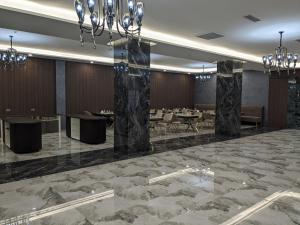 a lobby with tables and chairs and a chandelier at MirOtel in Shymkent