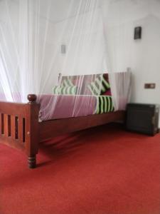 ein Holzbett mit Baldachin in einem Zimmer in der Unterkunft Ella Shali's home in Ella