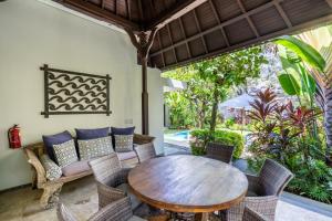 un patio al aire libre con mesa de madera y sillas en Kejora Beachfront Villas, en Sanur
