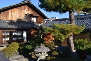 un giardino di fronte a una casa con un albero di Guesthouse Muga a Hikone