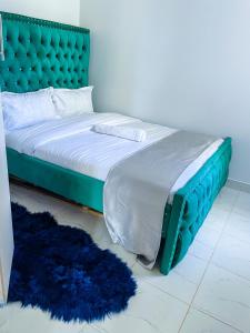 a bed with a green headboard and two blue rugs at Classy two bedroom Airbnb with swimming pool in Kiambu