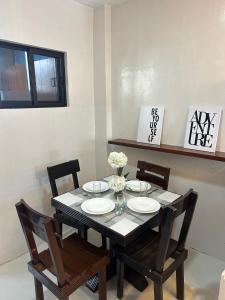 a dining room table and chairs with plates and flowers at Almar Apartelle in Oroquieta