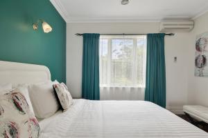 Schlafzimmer mit einem Bett mit grünen Vorhängen und einem Fenster in der Unterkunft Mt.Martha Guesthouse By The Sea in Mount Martha