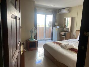 a bedroom with a bed and a room with a refrigerator at Hug me guesthouse in Pattaya Central