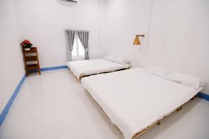 two beds in a white room with a window at Om Homestay in Tuy An