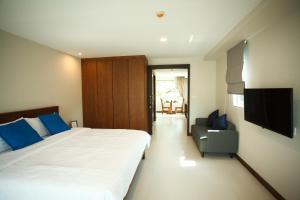 a bedroom with a bed and a tv and a chair at Nivas Chiangmai in Chiang Mai
