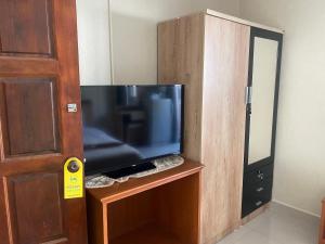 TV de pantalla plana dentro de un armario de madera en Hug me guesthouse, en Pattaya central