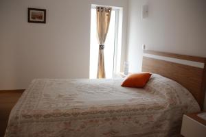 a bed with an orange pillow on it in a bedroom at Pátio da Caetana in Freineda