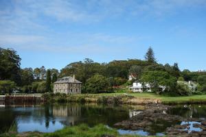 a house next to a body of water at Stone Store Lodge in Kerikeri
