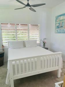 een wit bed in een slaapkamer met een plafondventilator bij Banana Bay Beach Club in Eton