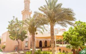 duży budynek z wieżą zegarową i palmami w obiekcie Discovery Gardens Haven Studio Units w Dubaju