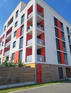 un edificio de apartamentos con balcones rojos y blancos en Sika Sunny Garden Apartment, en Arad