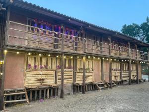 Bảo LạcにあるBao Lac Homestay Hostel & Coffeeの木製デッキ付きの建物で、バルコニーに人がいます。