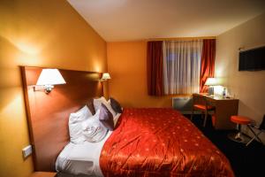 a hotel room with a bed and a desk at Logis Hôtel Restaurant La Palette in Wettolsheim