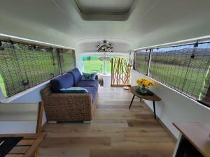 uma sala de estar num trailer com um sofá e janelas em Le Big Bus 