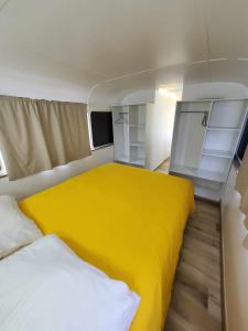 um pequeno quarto com uma cama e um cobertor amarelo em Le Big Bus 