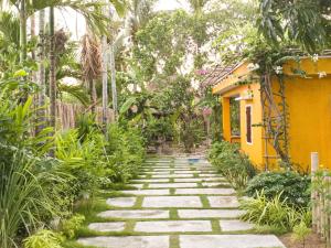 um caminho de pedra num jardim com uma casa amarela em Mango House Retreat Quy Nhon em Quy Nhon