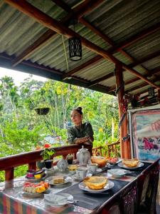 a woman sitting at a table with food on it at Cozy Homestay Waterfall Road Ella in Ella