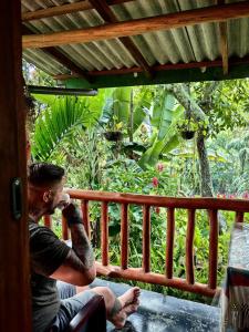 Un uomo seduto in veranda che parla al cellulare di Cozy Homestay Waterfall Road Ella a Ella
