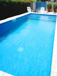 una gran piscina azul con 2 sillas. en บ้านพิม en Pran Buri