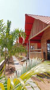 a building with a red roof with palm trees in front of it at Osho's Organic Resort Hampi in Hampi
