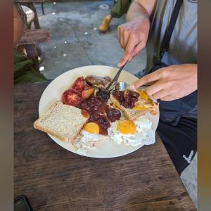 una persona comiendo un plato de desayuno con huevos y tostadas en Imchai en Pai