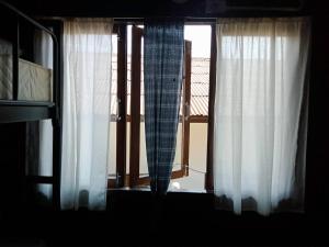ein Fenster mit weißen Vorhängen und Blick auf einen Balkon in der Unterkunft Imchai in Pai