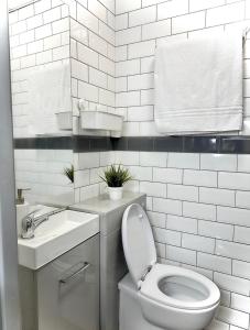 Baño blanco con aseo y lavamanos en Papaya’s en-suite en Hoyland Nether