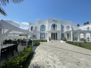 a white building with tables and chairs in front of it at Blanco boutique hotel astara in Astara