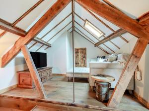 a loft conversion with a room with a couch and a tv at Bockety Barn in Stalham