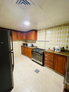 a kitchen with wooden cabinets and a stove top oven at Sam Home in Sharjah