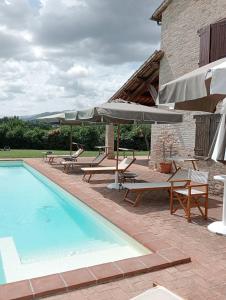a pool with chairs and umbrellas next to a building at Parco Ducale Country House in Urbania