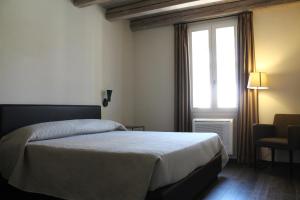 una camera con letto, finestra e sedia di PALAZZO DE' ROSSI HOTEL a Sasso Marconi