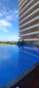 a large building with a swimming pool in front of it at Apartemen Nuvasa Bay in Nongsa