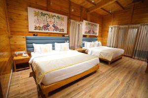 two beds in a room with wooden walls at Regenta Resort Sakleshpur in Sakleshpur