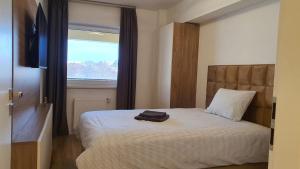 a small bedroom with a bed with a window at Apartament Comfortable Fortuna in Sfântu-Gheorghe