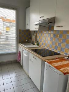 una cocina con armarios blancos y una pared de azulejos en Appartement spacieux Gentilly, en Gentilly