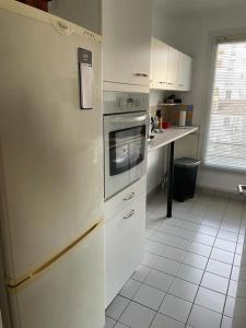 La cuisine est équipée d'un réfrigérateur blanc et d'un évier. dans l'établissement Appartement spacieux Gentilly, à Gentilly