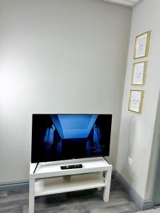 a flat screen tv sitting on a white tv stand at Papaya’s en-suite in Hoyland Nether