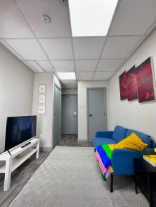 a living room with a blue couch and a tv at Papaya’s en-suite in Hoyland Nether