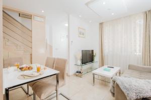 a white living room with a table and a tv at Apartman Mija in Split