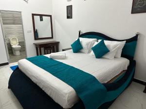 a bedroom with a large bed with blue and white sheets at Trinco Waves in Trincomalee