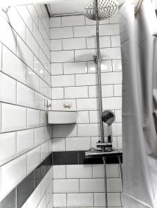 baño de azulejos blancos con ducha y secador de pelo en Papaya’s en-suite, en Hoyland Nether