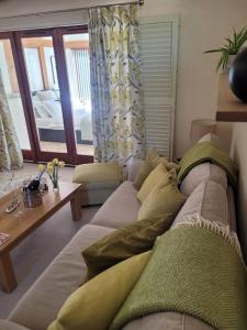 uma sala de estar com um sofá e uma mesa em Honeysuckle Cottage Annex with hot tub near Needham Market em Needham Market