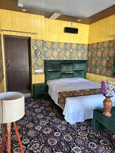 - une chambre avec un lit et un vase de fleurs dans l'établissement Hideaway Cottages "Home in Kashmir", à Gulmarg