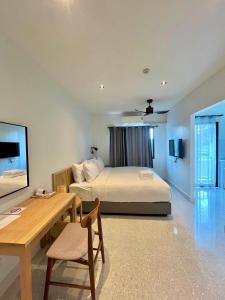 a bedroom with a bed and a table and a desk at Calamint Residence Hotel ( คาลามิ้นท์) in Chumphon