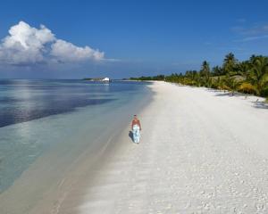 Ein Mann, der an einem Strand im Meer wandelt in der Unterkunft South Palm Resort Maldives with First-ever floating Spa in Midu